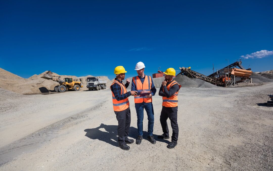 Three mining geological workers standing and discussing at an open-pit mine