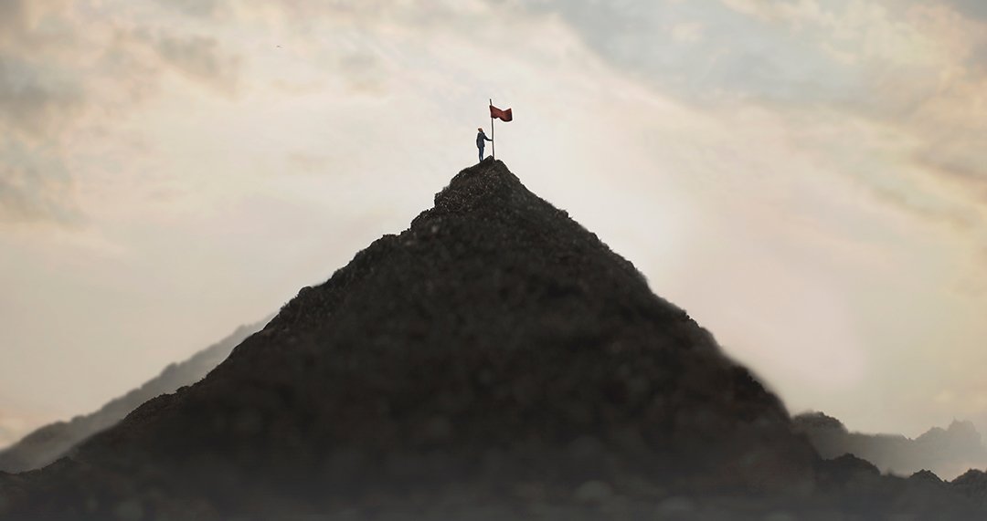 Prospector planting flag on top of mountain to signify a land claim