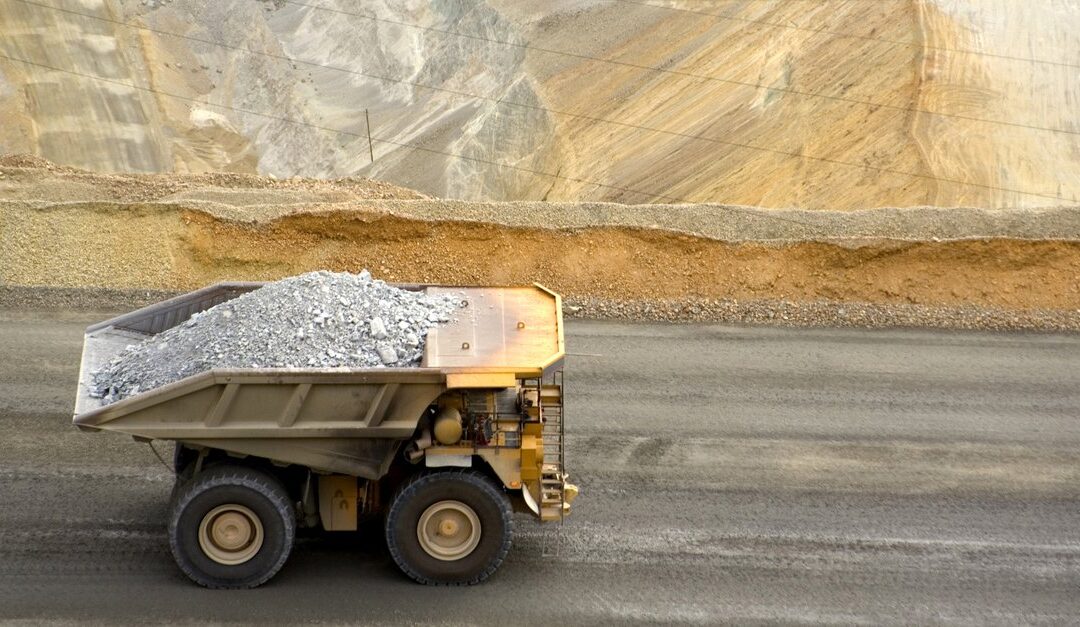 Large yellow dump truck with rock in open pit mine